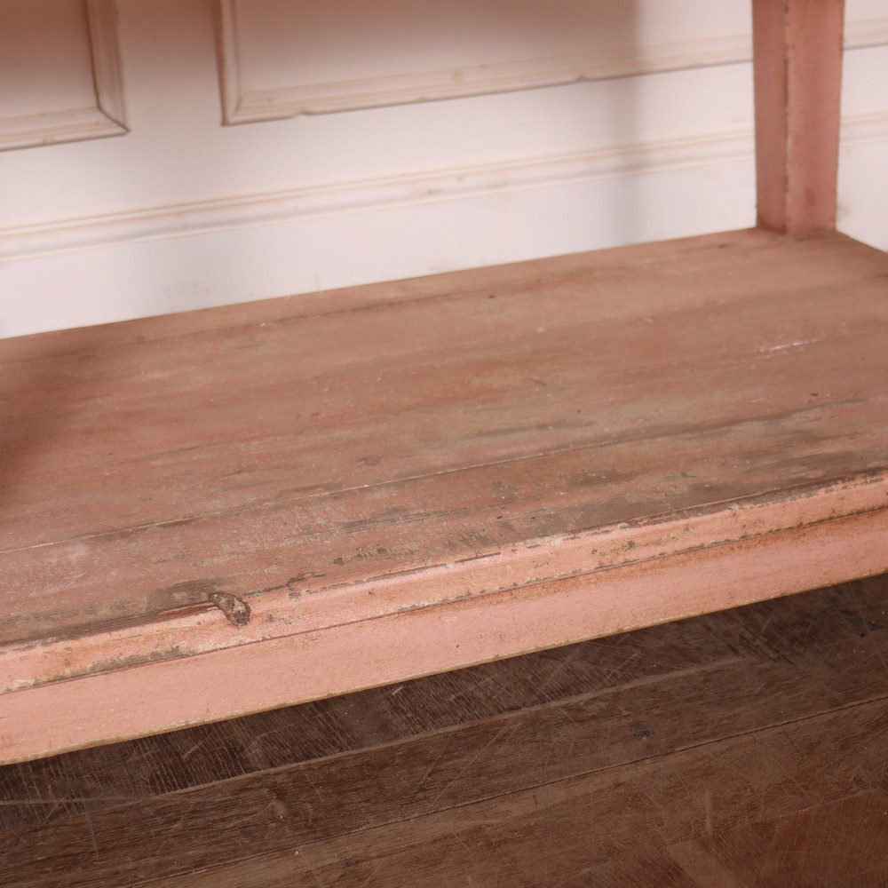 A Scottish farmhouse potboard dresser base with a painted pink frame, wide drawers fitted with brass handles, and an open lower wooden shelf. View VII