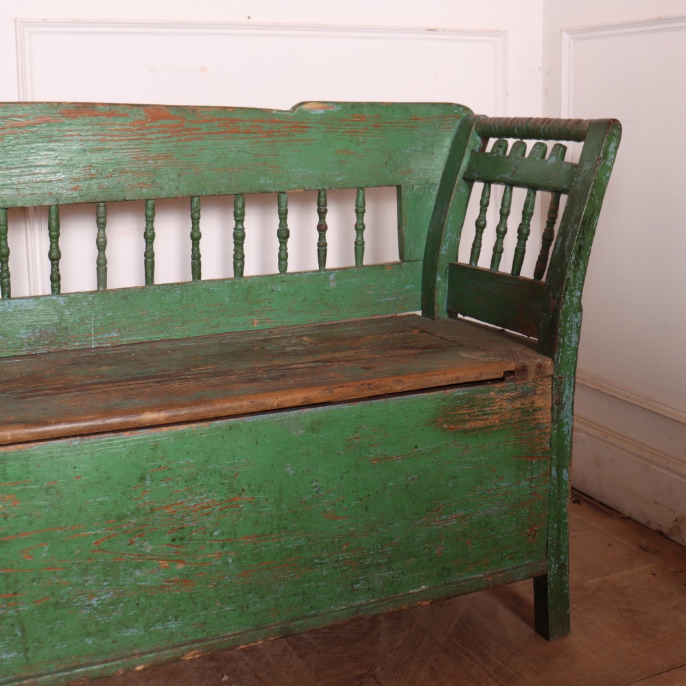 An antique green painted pine settle bench featuring a spindle backrest and a hinged storage seat base. View II