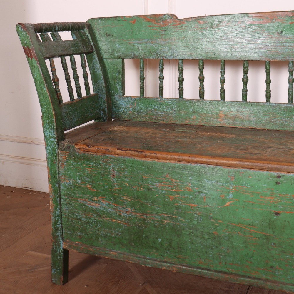 An antique green painted pine settle bench featuring a spindle backrest and a hinged storage seat base. View III