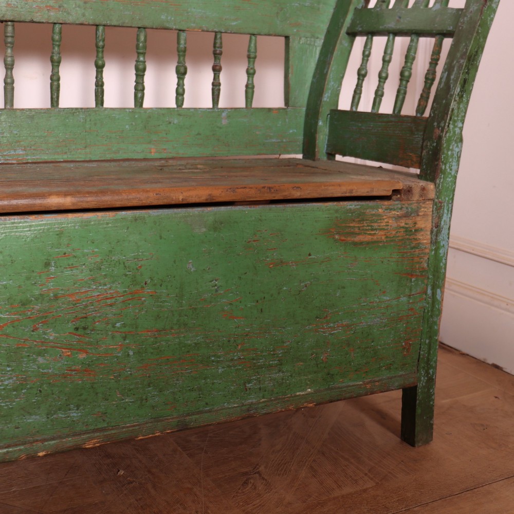 An antique green painted pine settle bench featuring a spindle backrest and a hinged storage seat base. View VI