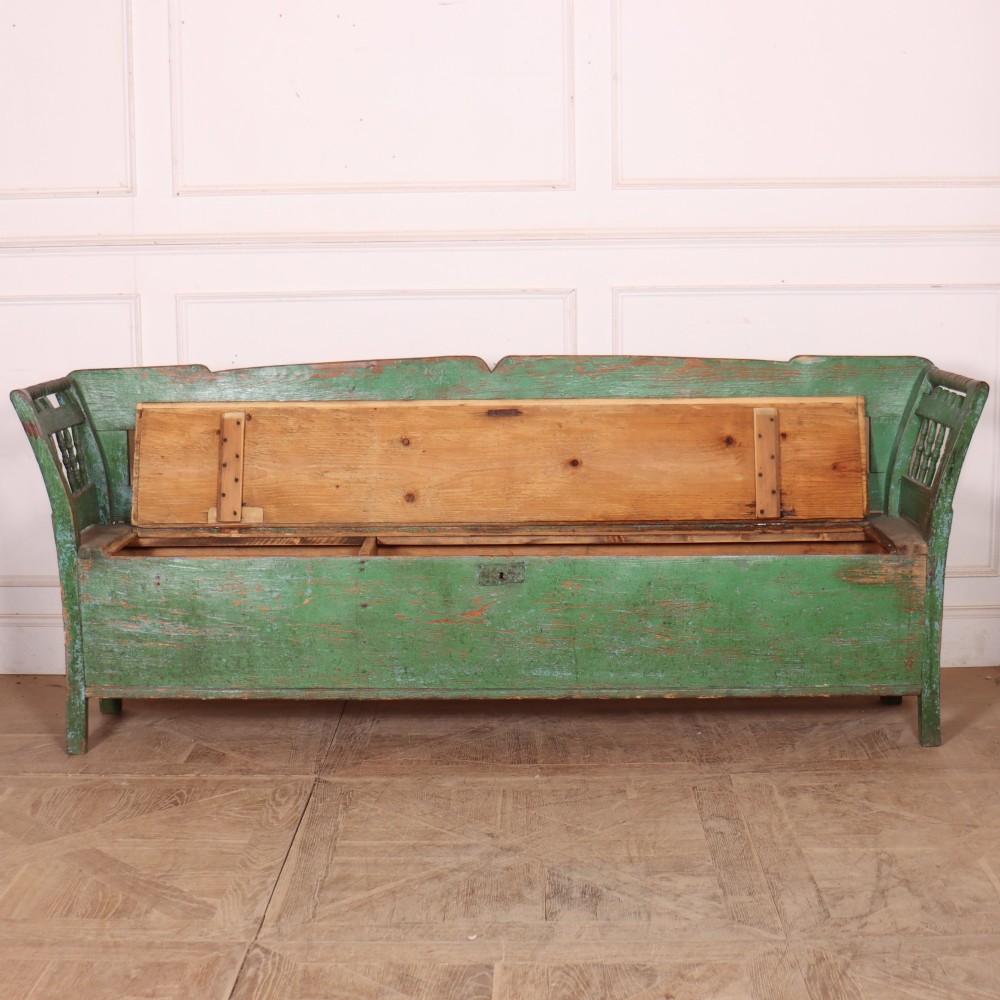An antique green painted pine settle bench featuring a spindle backrest and a hinged storage seat base. View VII