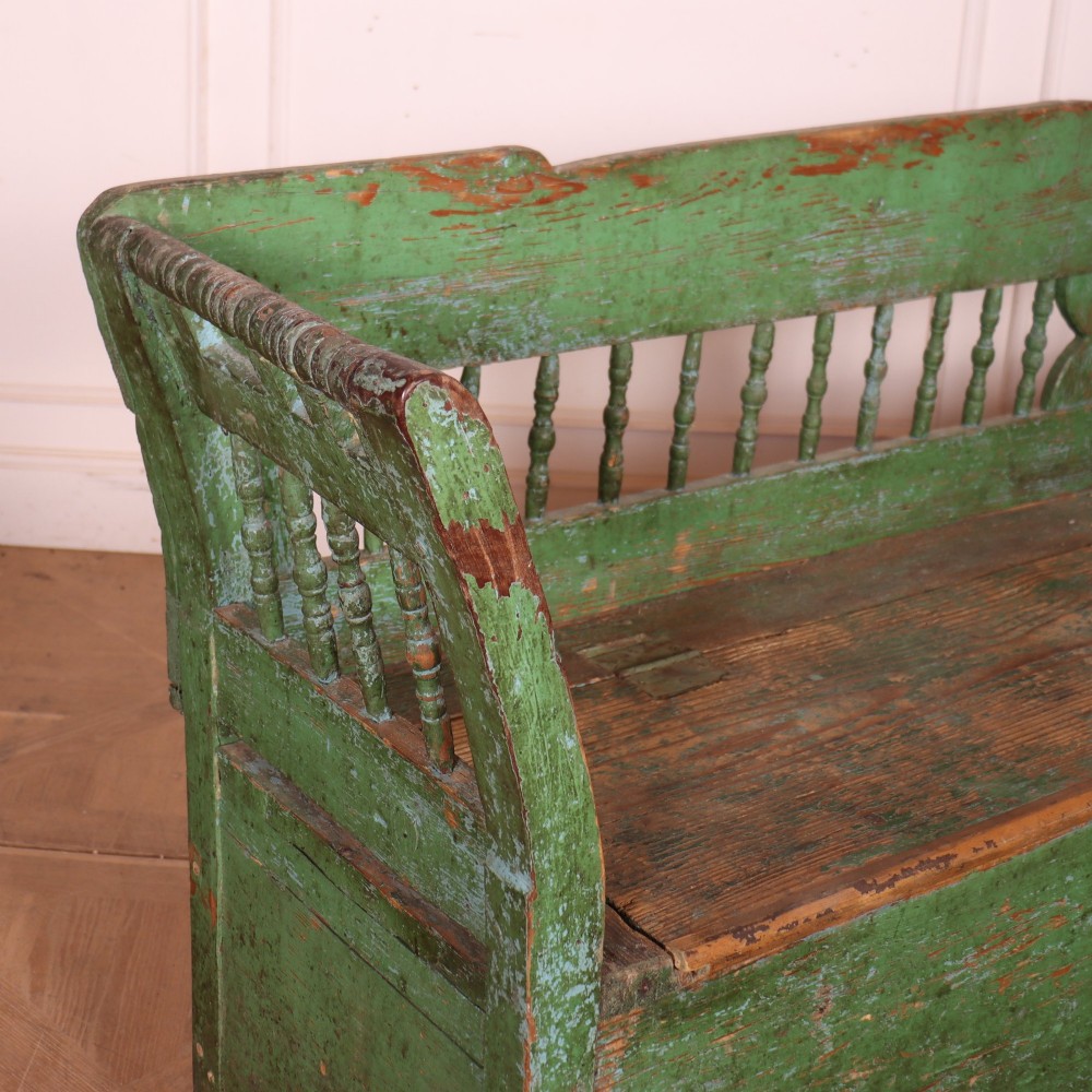 An antique green painted pine settle bench featuring a spindle backrest and a hinged storage seat base. View IX
