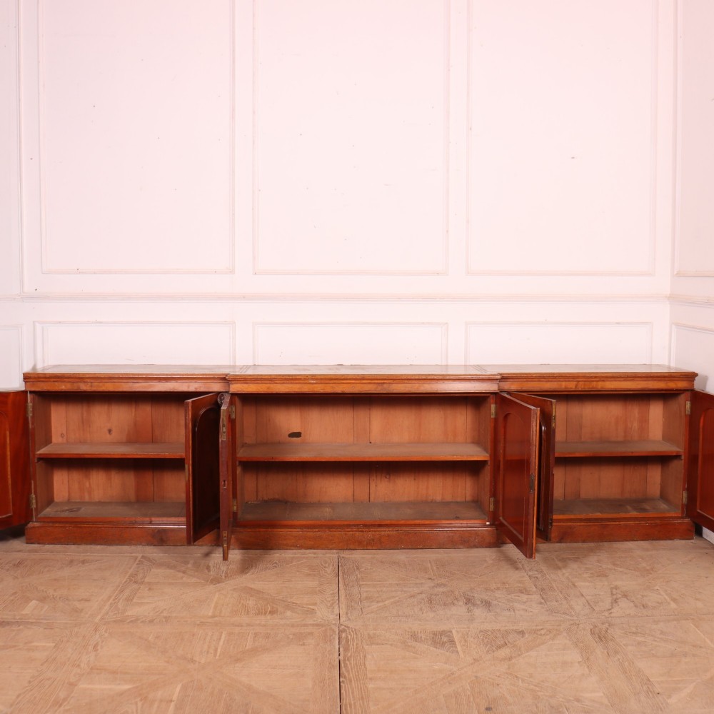 An antique English burr walnut dresser base featuring six arched cupboard doors with hand-carved decorative corbels along the top moulding. View X