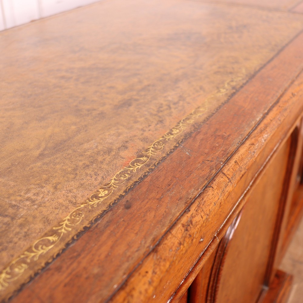 An antique English burr walnut dresser base featuring six arched cupboard doors with hand-carved decorative corbels along the top moulding. View XIV