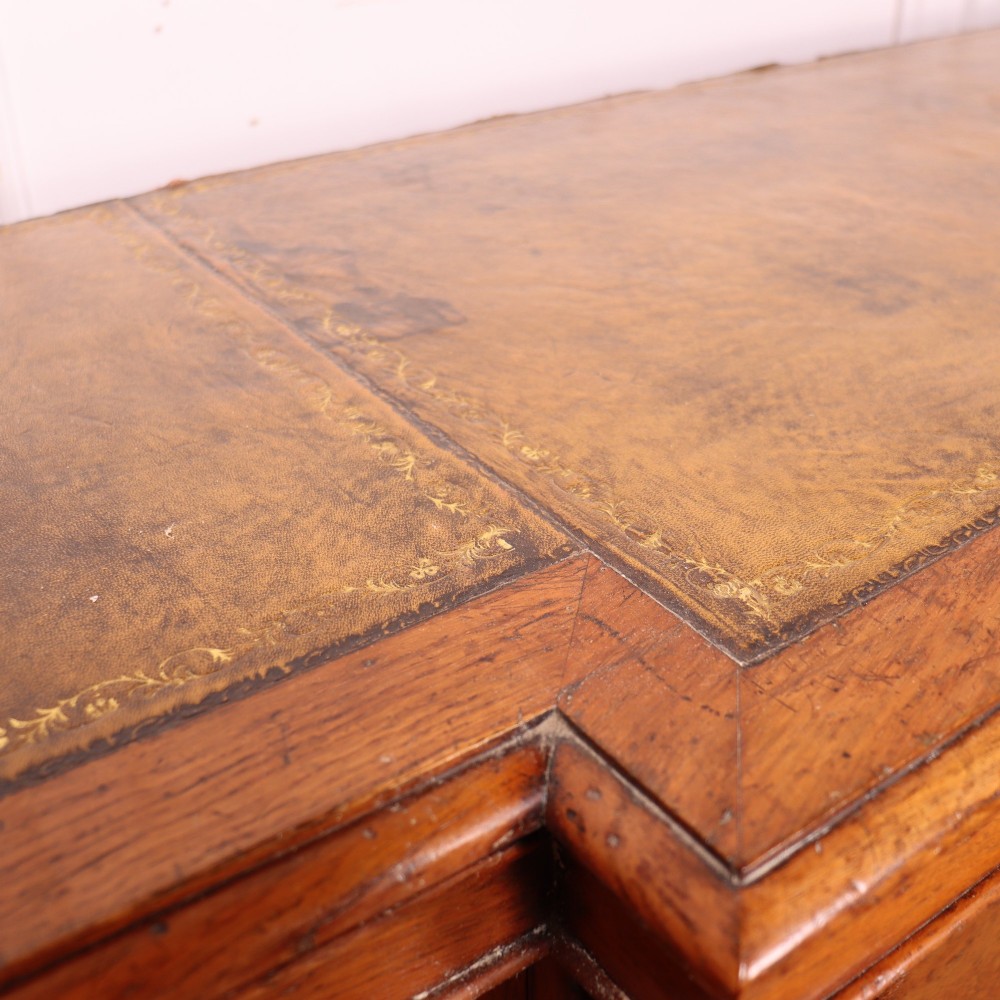 An antique English burr walnut dresser base featuring six arched cupboard doors with hand-carved decorative corbels along the top moulding. View XV