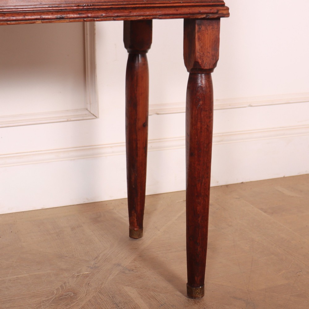 An antique English pine kitchen dresser featuring an open tiered plate rack above three drawers with brass handles, resting on slender turned legs. View V