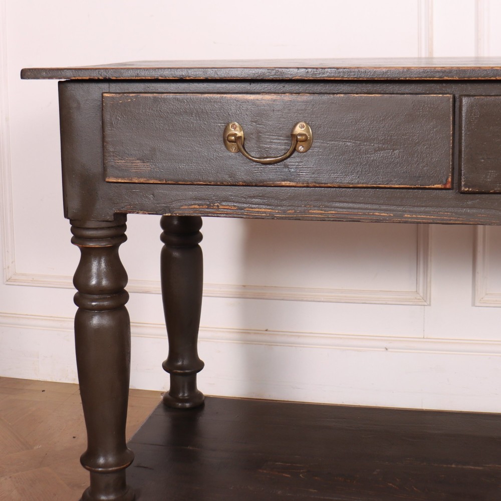 An antique dark grey painted English potboard dresser base featuring four drawers with brass handles, turned legs, and an open lower shelf. View II