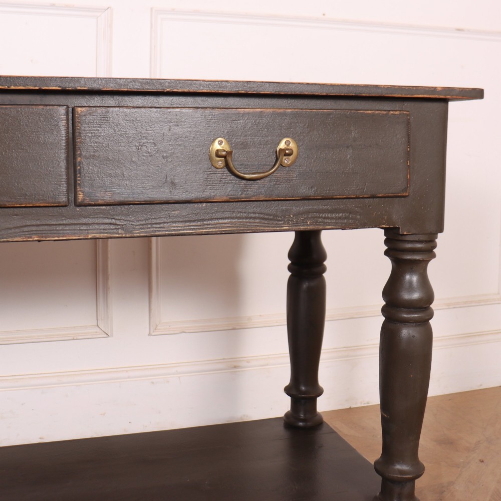 An antique dark grey painted English potboard dresser base featuring four drawers with brass handles, turned legs, and an open lower shelf. View V