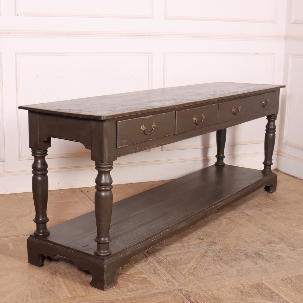 An antique dark grey painted English potboard dresser base featuring four drawers with brass handles, turned legs, and an open lower shelf. View VIII