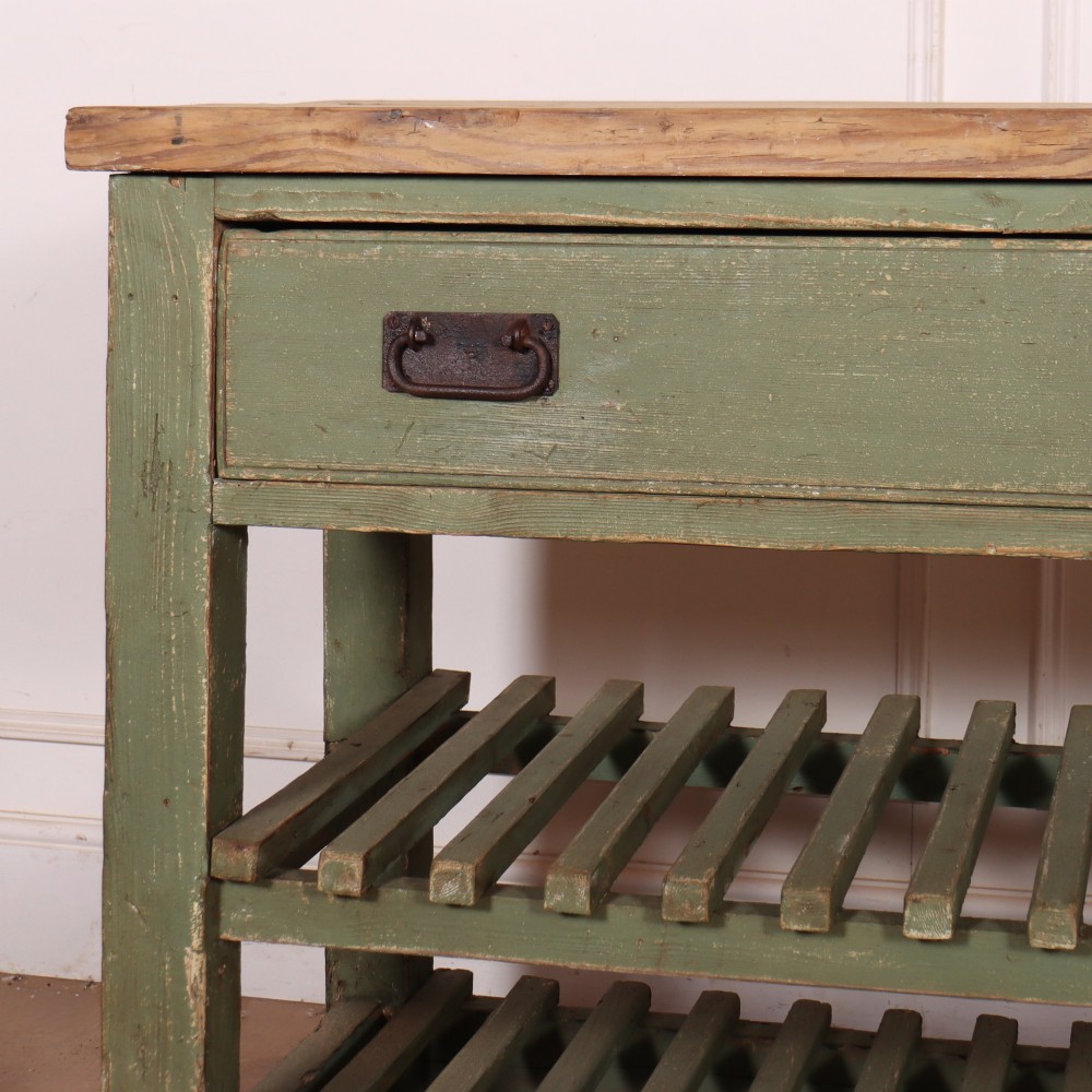 A rustic green painted Scottish dresser base with an unpainted pine top, two drawers with iron metal drop handles, and two slatted lower shelves. View II