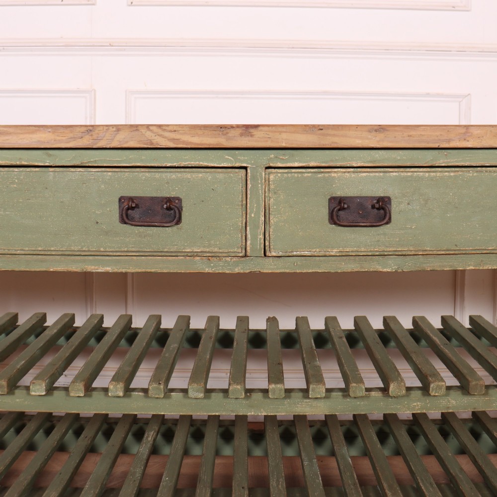 A rustic green painted Scottish dresser base with an unpainted pine top, two drawers with iron metal drop handles, and two slatted lower shelves. View IV