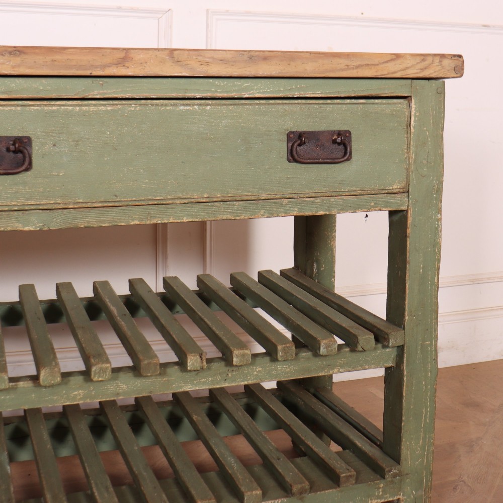 A rustic green painted Scottish dresser base with an unpainted pine top, two drawers with iron metal drop handles, and two slatted lower shelves. View VI