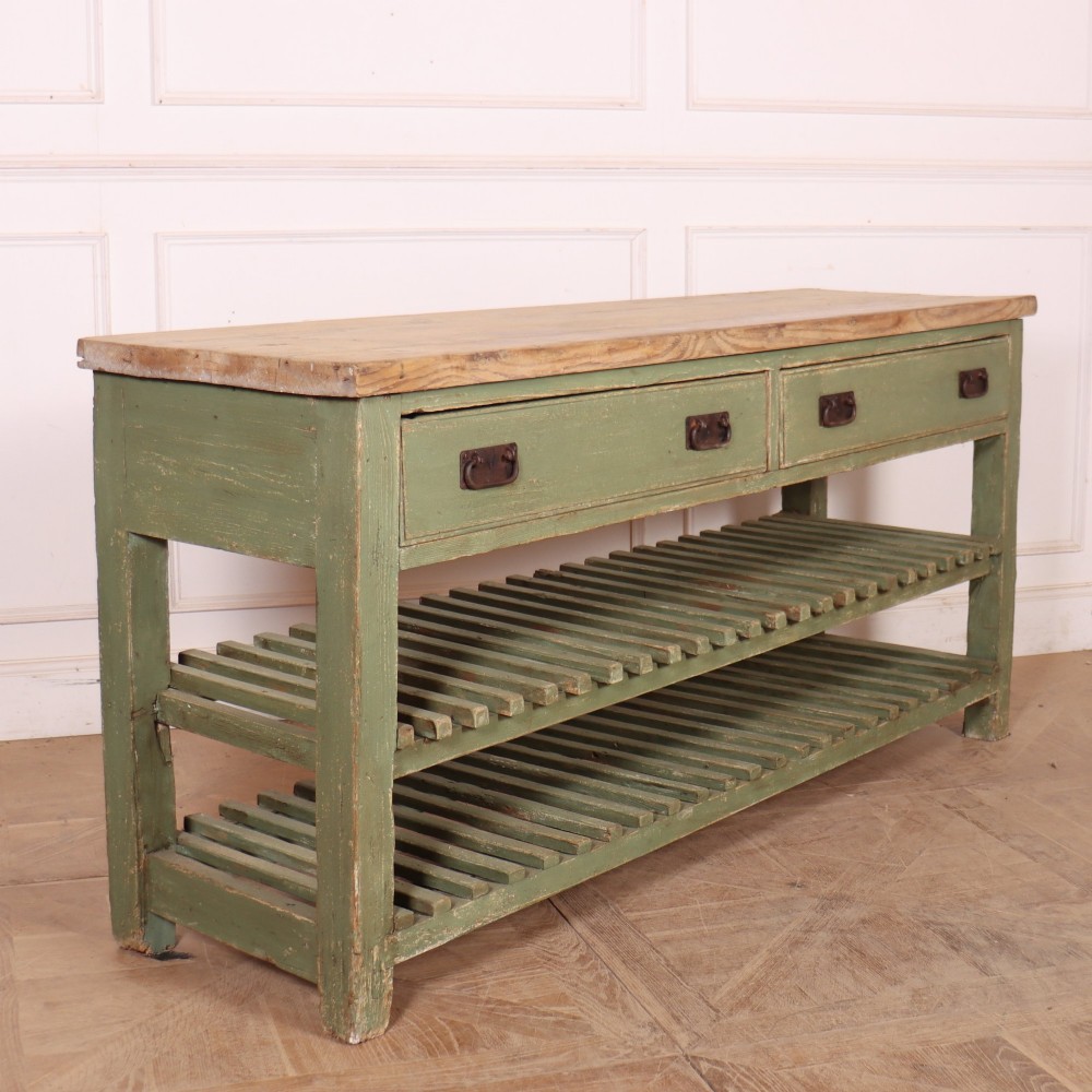 A rustic green painted Scottish dresser base with an unpainted pine top, two drawers with iron metal drop handles, and two slatted lower shelves. View X