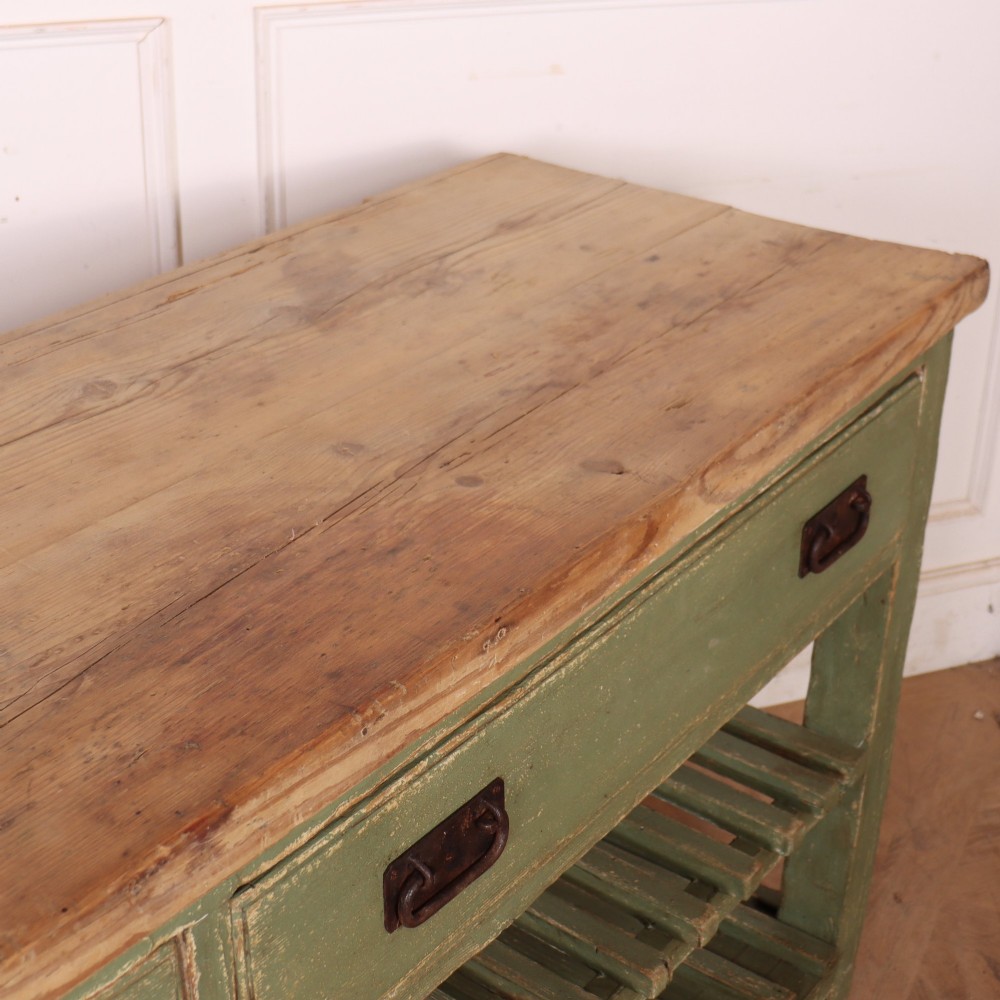 A rustic green painted Scottish dresser base with an unpainted pine top, two drawers with iron metal drop handles, and two slatted lower shelves. View XIV