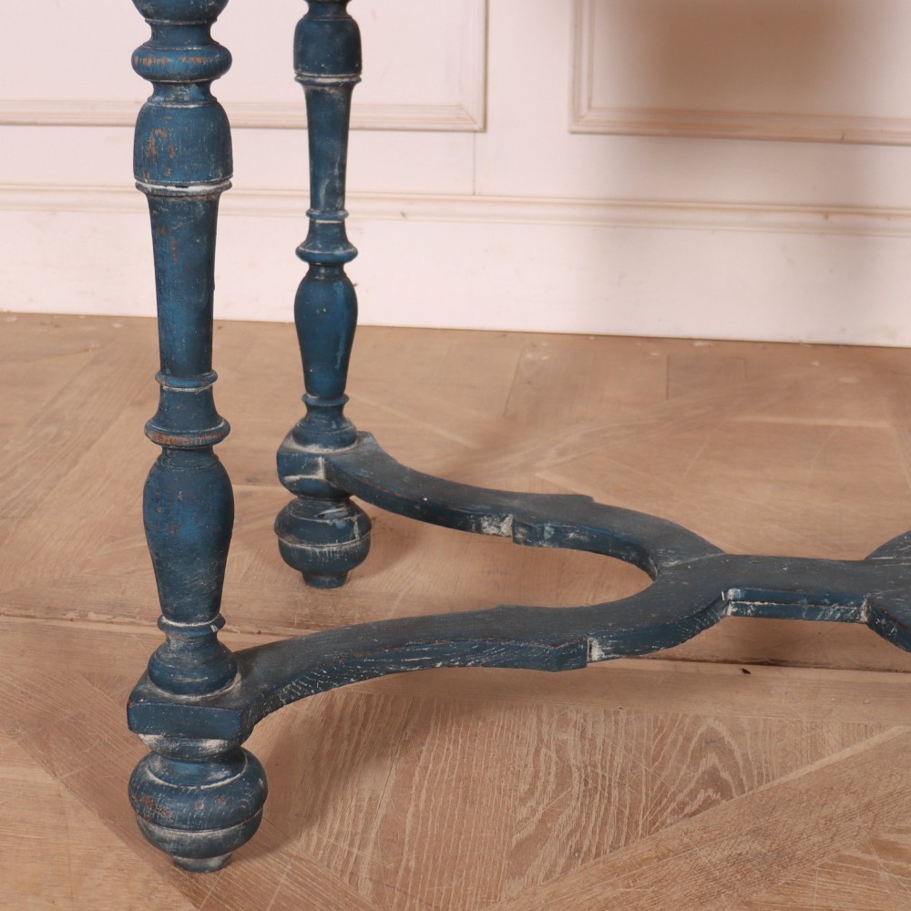 A rectangular blue painted wooden lamp table featuring turned legs, a single drawer with a metal pull, a scalloped apron, and a curved X-shaped stretcher. View III
