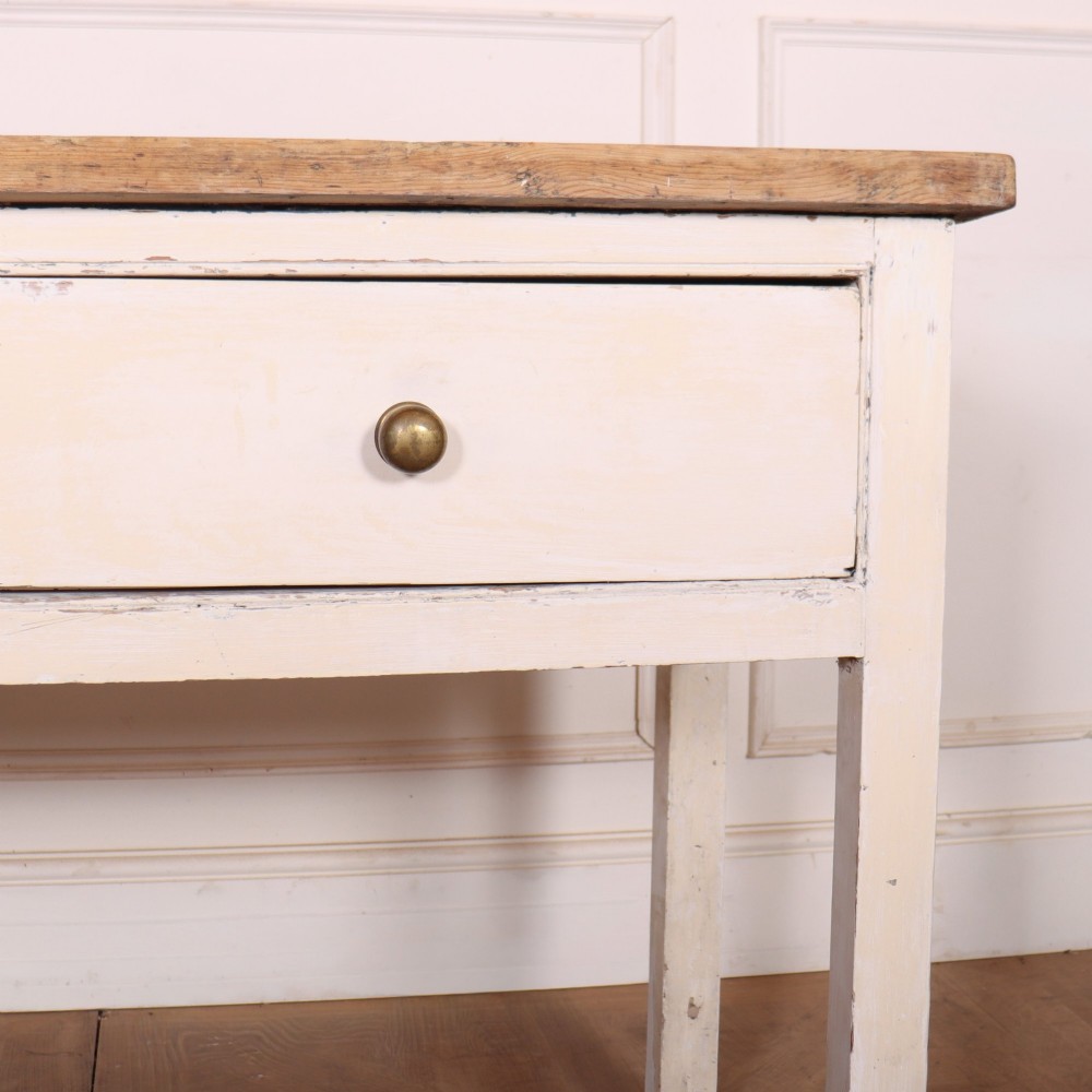 An antique English country dresser base featuring a natural wooden top, three off-white painted drawers with circular brass knobs, and four square straight legs. View V