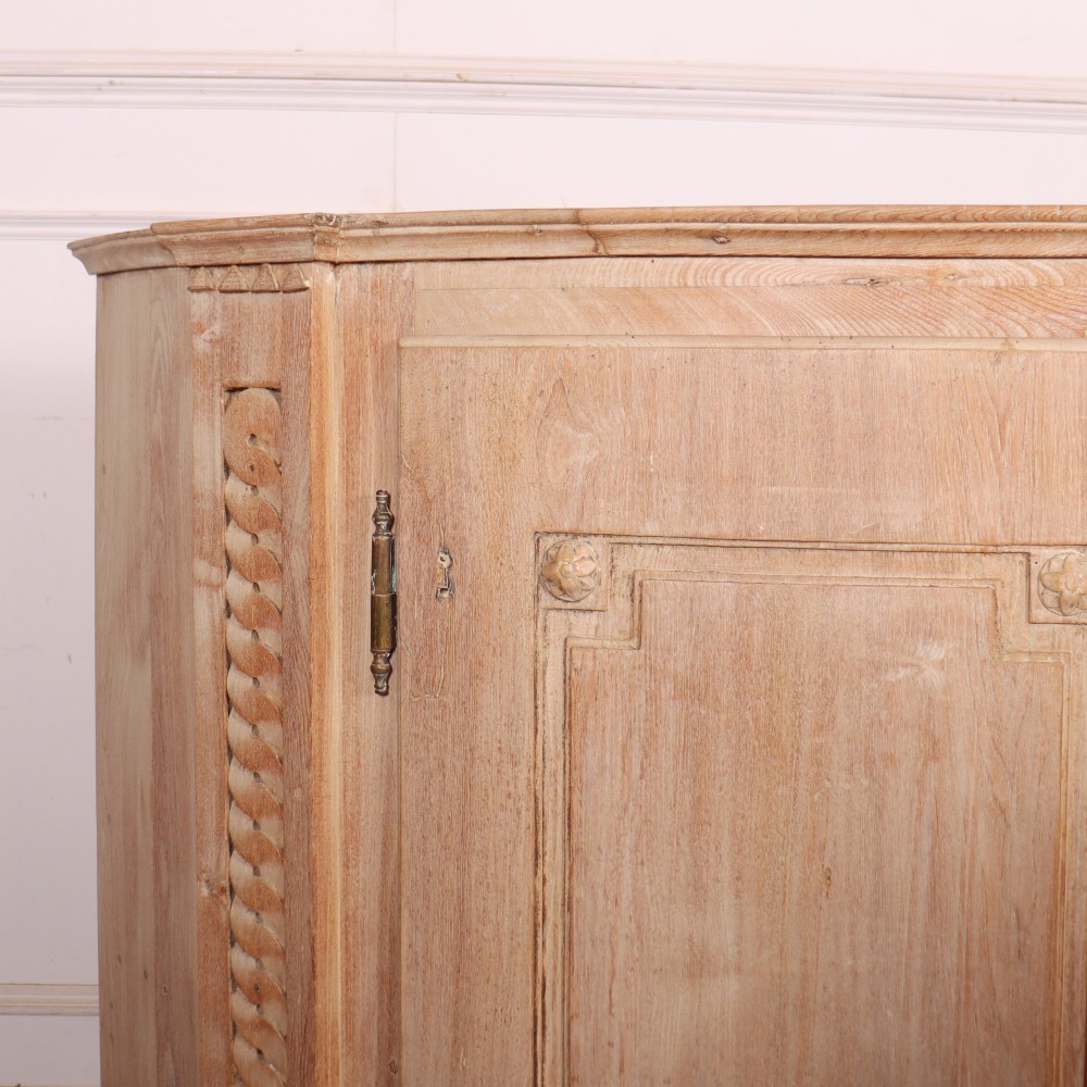 A pale wood bowfront buffet featuring two panelled doors, carved side detailing, and brass keyholes. View II