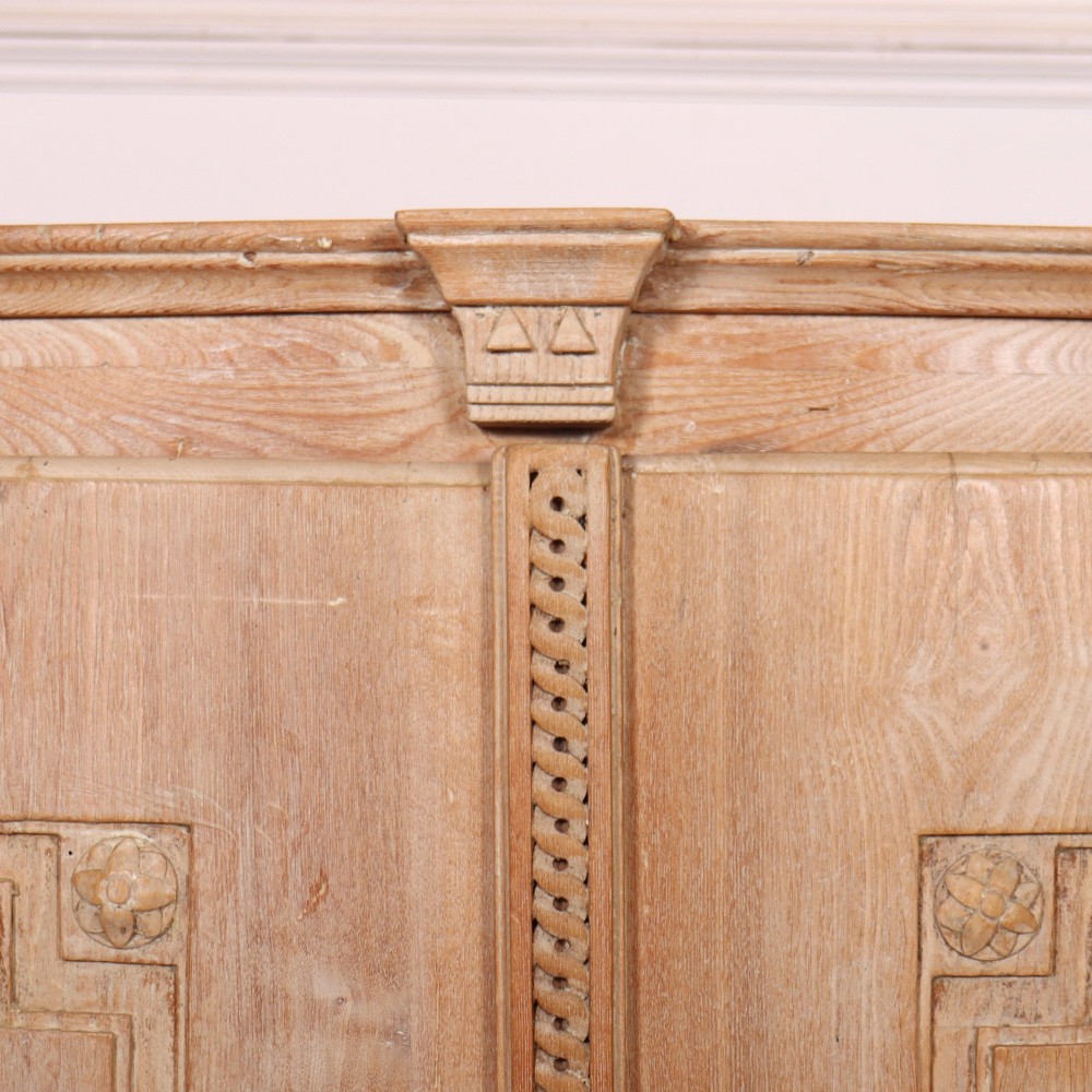 A pale wood bowfront buffet featuring two panelled doors, carved side detailing, and brass keyholes. View IV