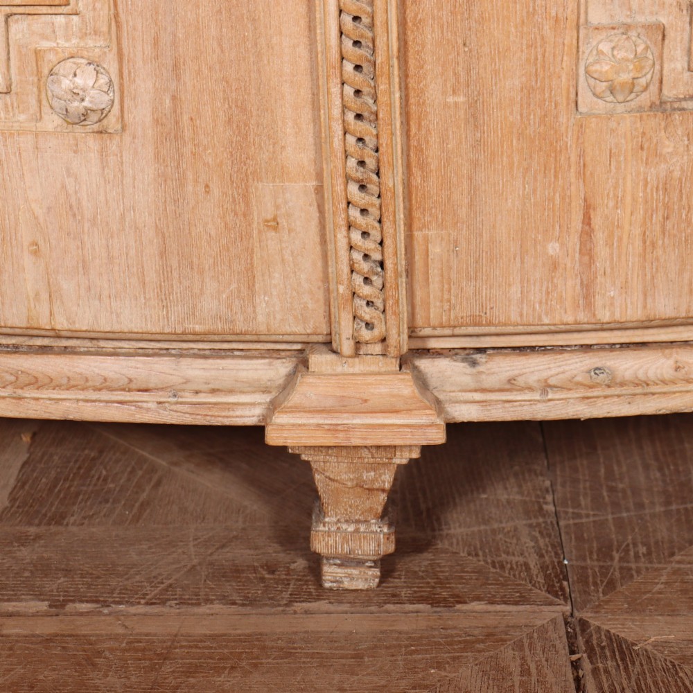 A pale wood bowfront buffet featuring two panelled doors, carved side detailing, and brass keyholes. View V