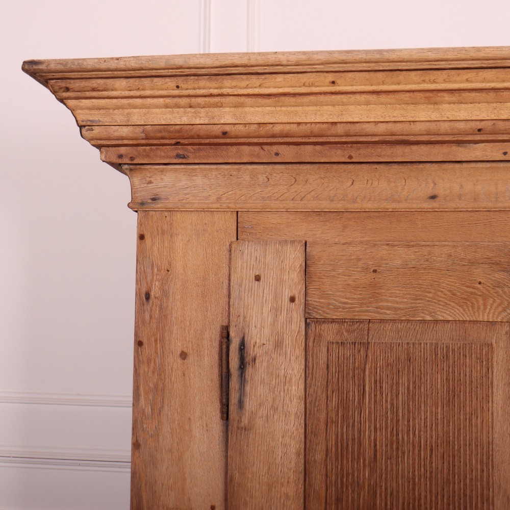 A freestanding antique Danish oak wardrobe featuring a flared top cornice, double doors with reeded panels, and heavy turned bun feet. View II