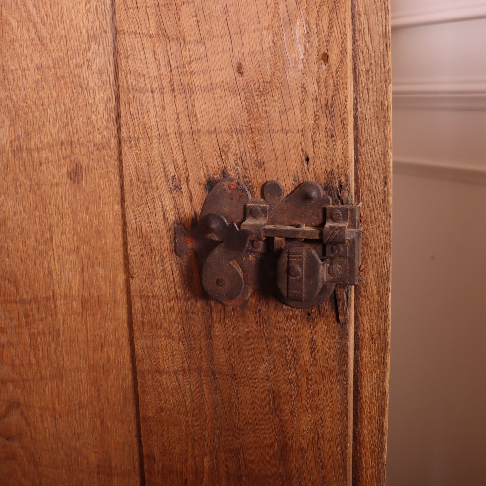 A freestanding antique Danish oak wardrobe featuring a flared top cornice, double doors with reeded panels, and heavy turned bun feet. View VII