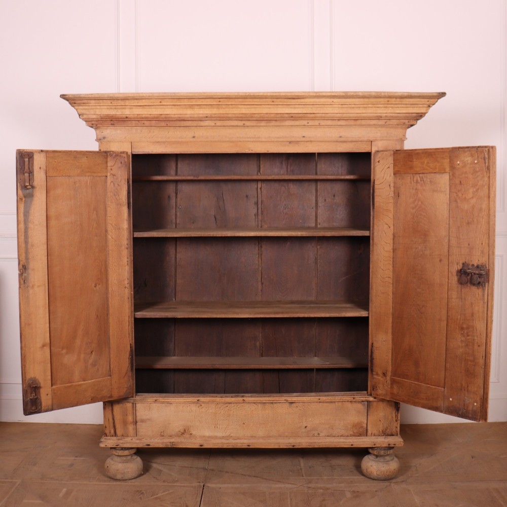 A freestanding antique Danish oak wardrobe featuring a flared top cornice, double doors with reeded panels, and heavy turned bun feet. View VIII