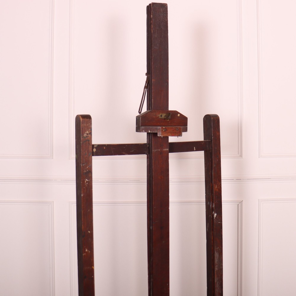 A floor-standing antique dark oak studio easel featuring an adjustable vertical central mast and a wide H-frame base with castors. View II