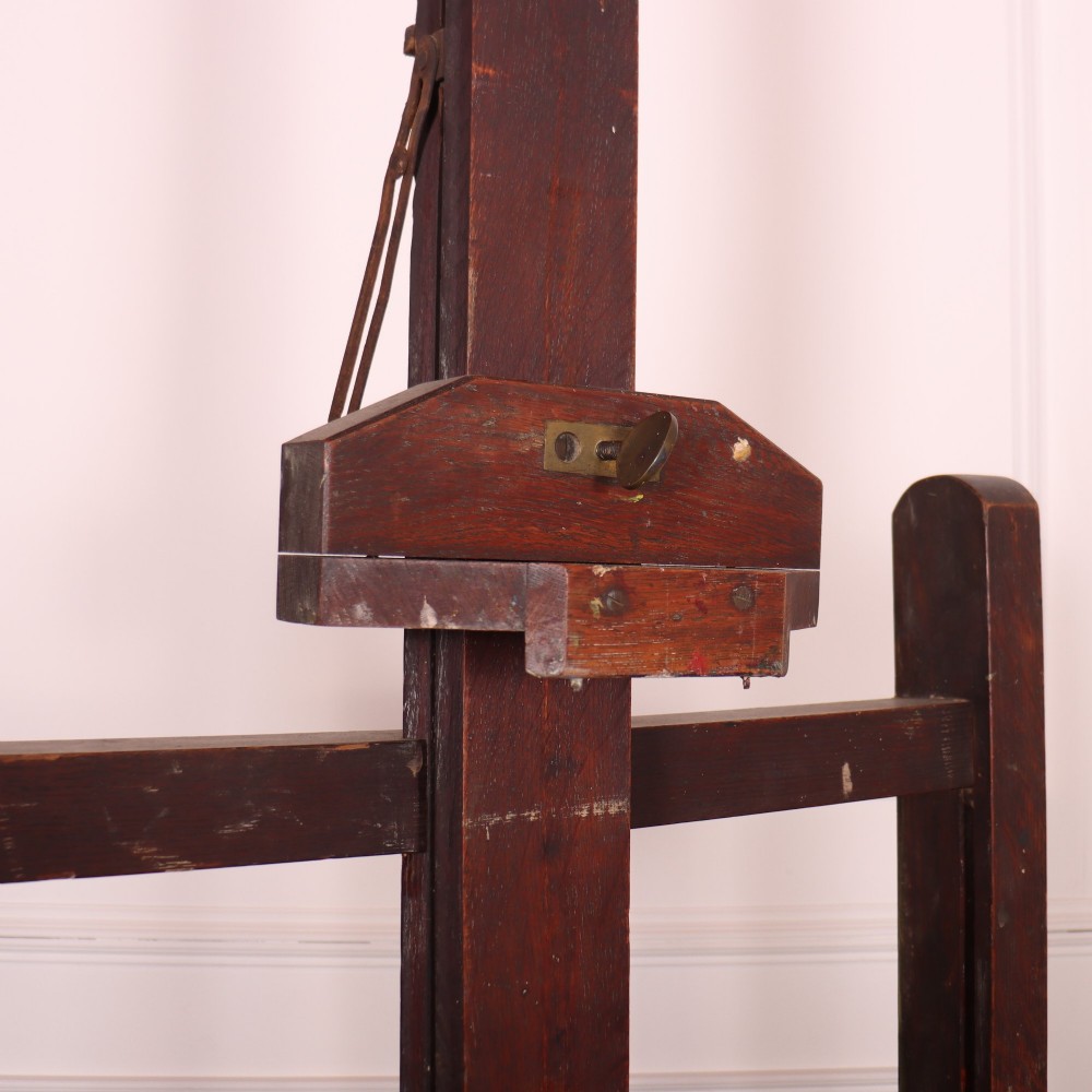 A floor-standing antique dark oak studio easel featuring an adjustable vertical central mast and a wide H-frame base with castors. View III