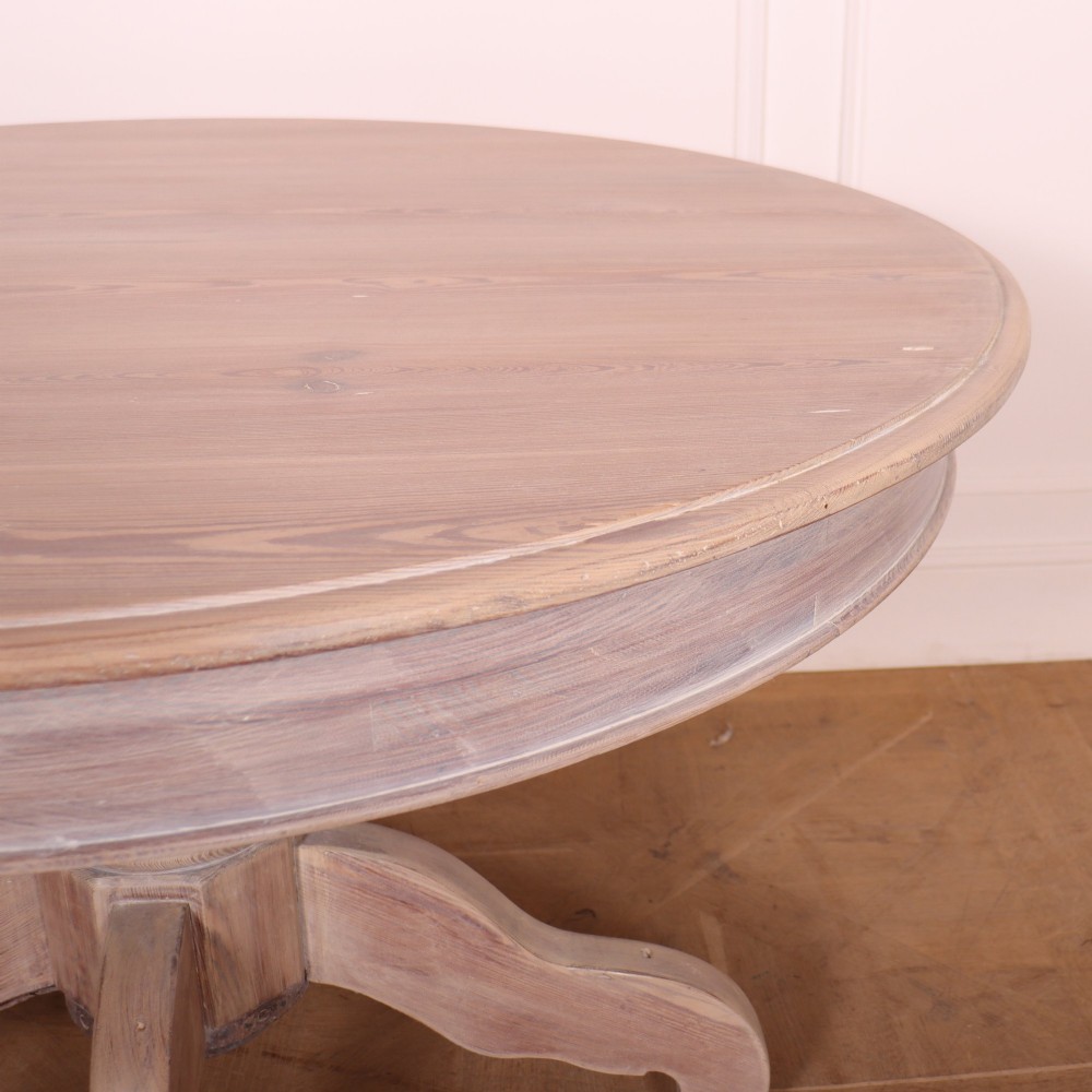 A circular bleached oak breakfast table with a thick turned central pedestal and four splayed legs. View III