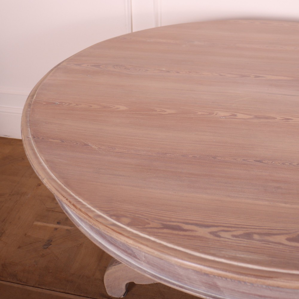 A circular bleached oak breakfast table with a thick turned central pedestal and four splayed legs. View IV