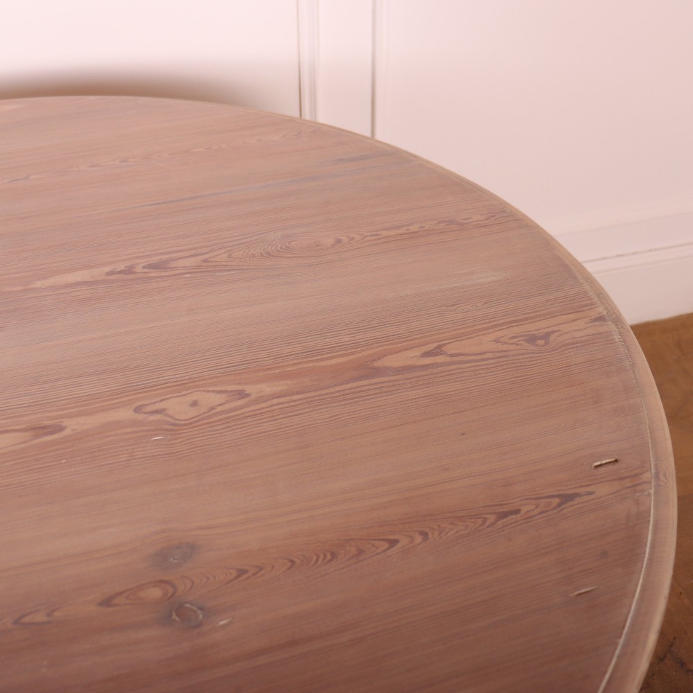 A circular bleached oak breakfast table with a thick turned central pedestal and four splayed legs. View V