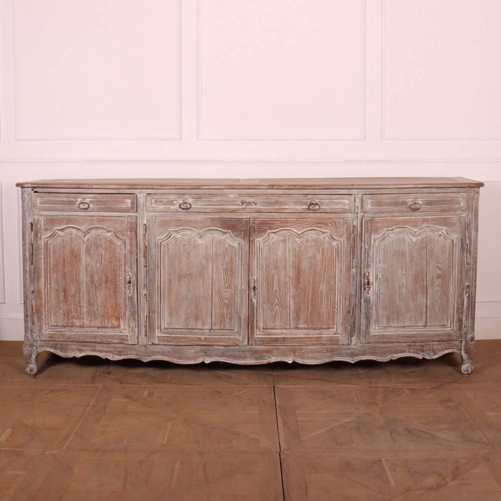 A large four-door French provincial enfilade made from bleached oak, featuring raised panel cupboard doors, four top drawers, and a scalloped apron.