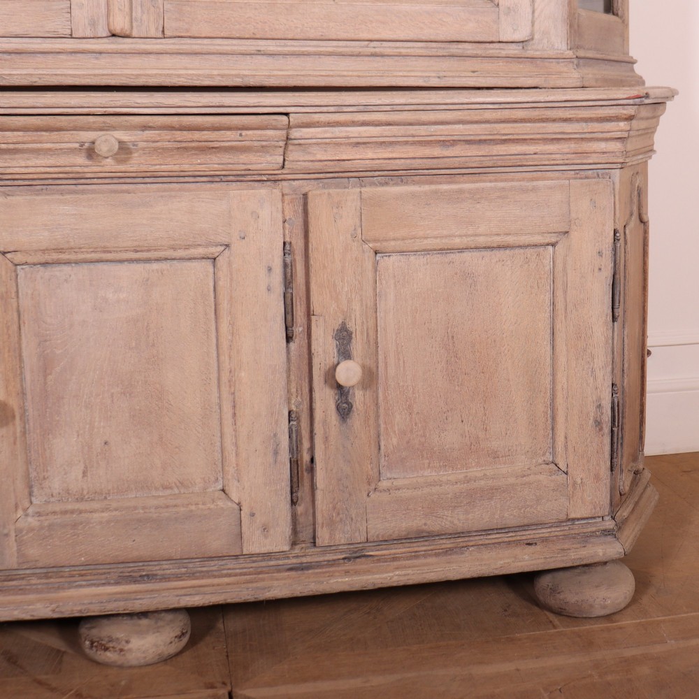 A large Dutch bleached oak display cabinet featuring an arched glazed top section with glass doors and a lower cupboard base supported on bun feet. View IV