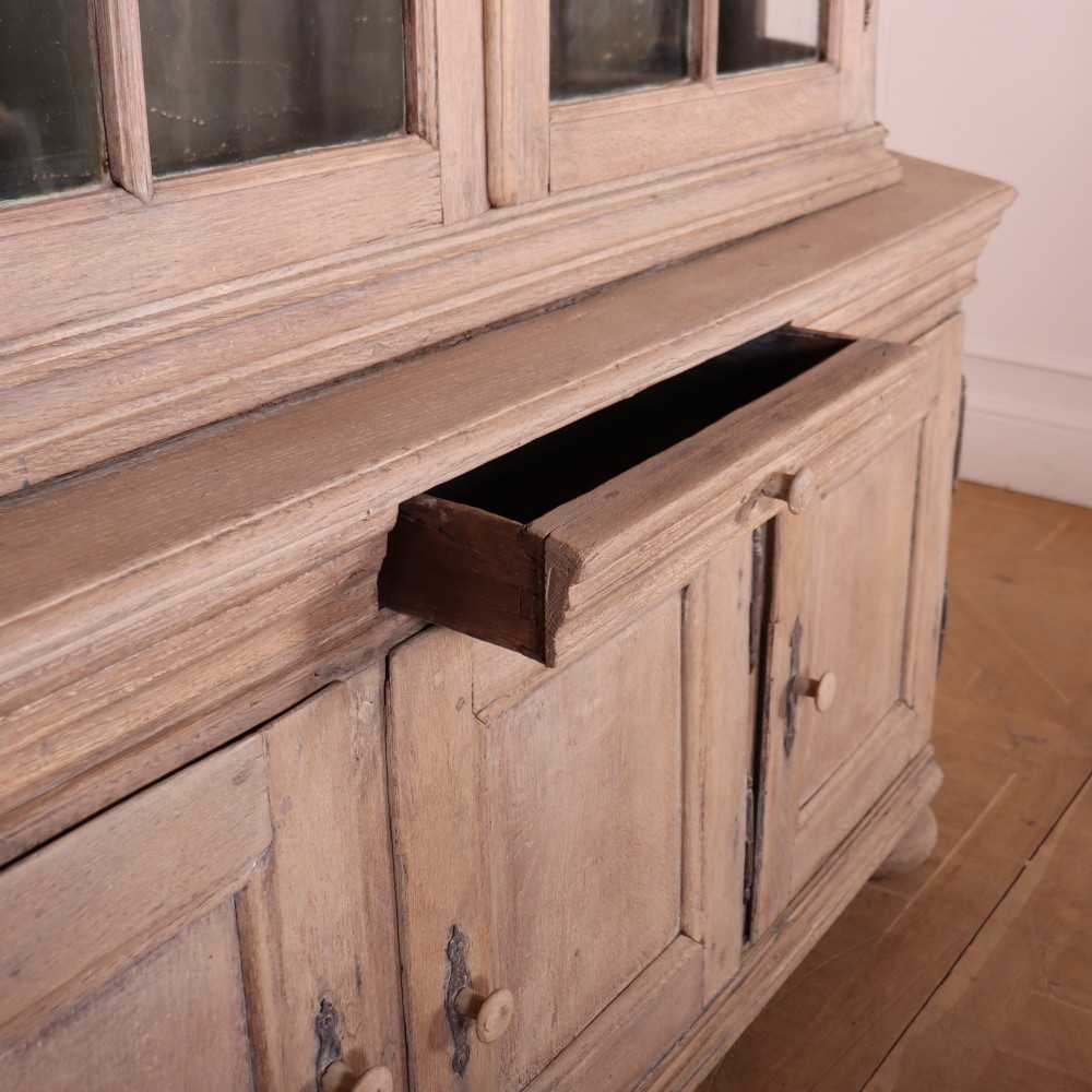 A large Dutch bleached oak display cabinet featuring an arched glazed top section with glass doors and a lower cupboard base supported on bun feet. View V