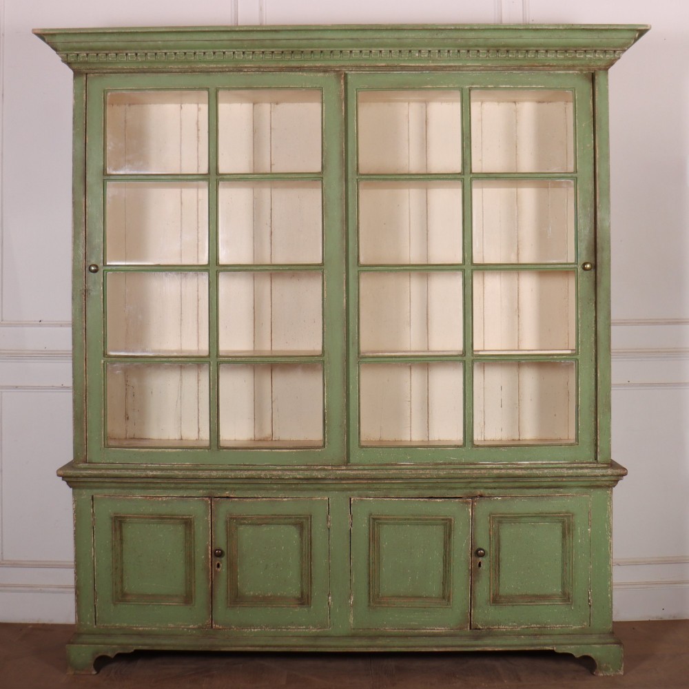 A large green painted timber cabinet featuring a two-door glazed upper section with multiple glass panes above a four-door solid panelled lower cupboard.