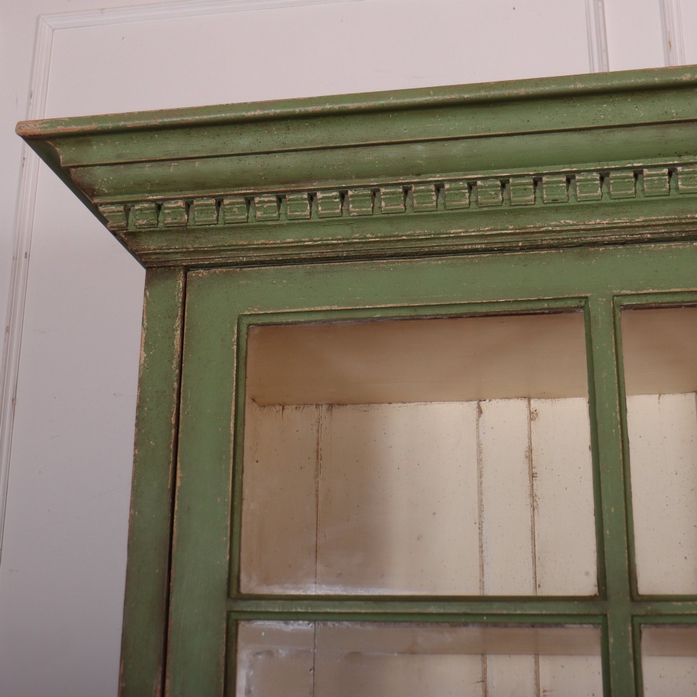 A large green painted timber cabinet featuring a two-door glazed upper section with multiple glass panes above a four-door solid panelled lower cupboard. View II