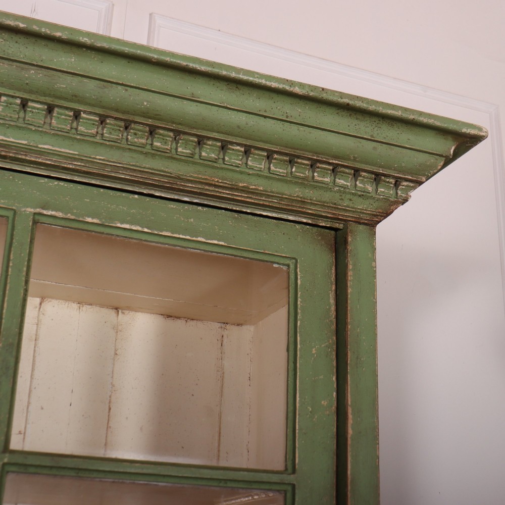 A large green painted timber cabinet featuring a two-door glazed upper section with multiple glass panes above a four-door solid panelled lower cupboard. View III