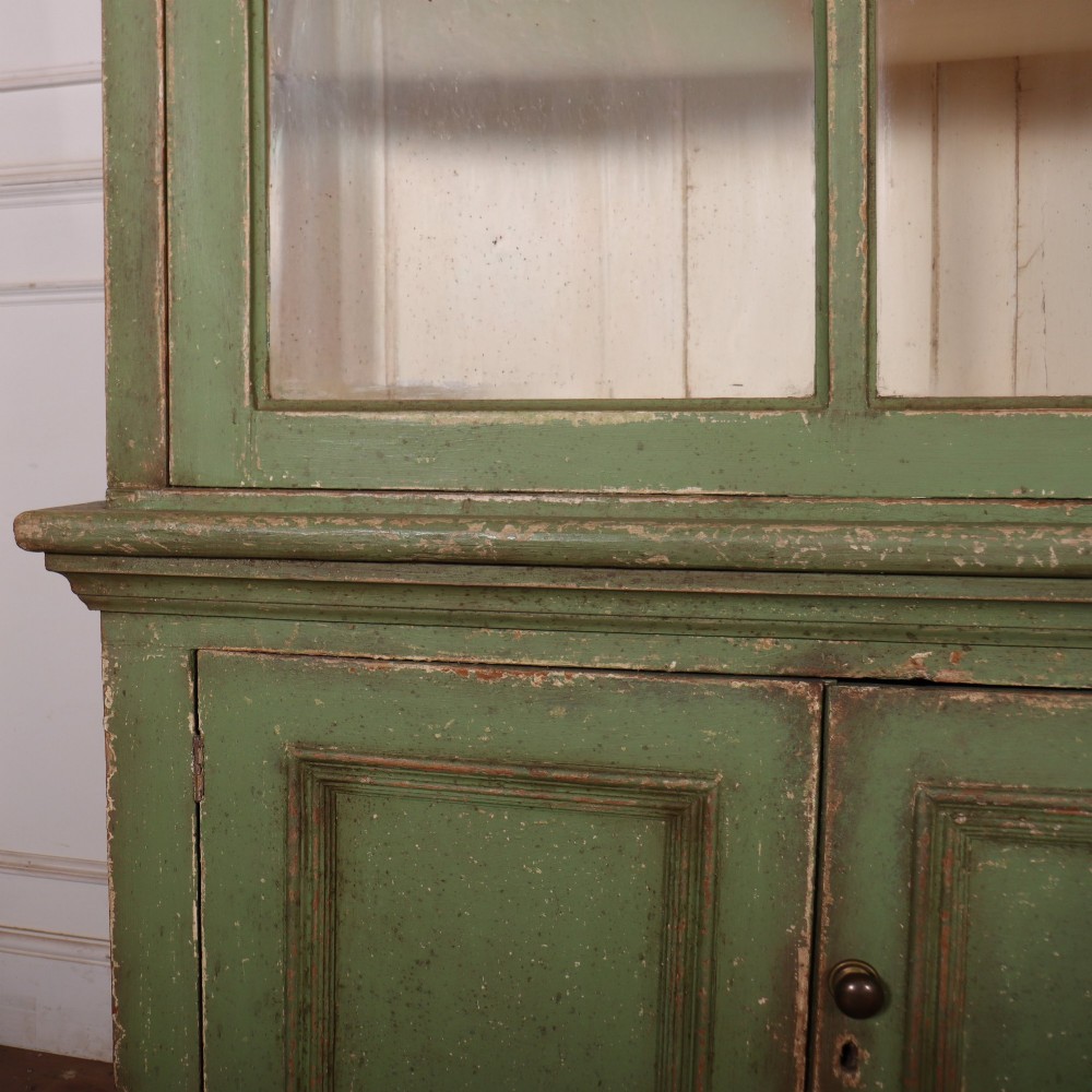A large green painted timber cabinet featuring a two-door glazed upper section with multiple glass panes above a four-door solid panelled lower cupboard. View V
