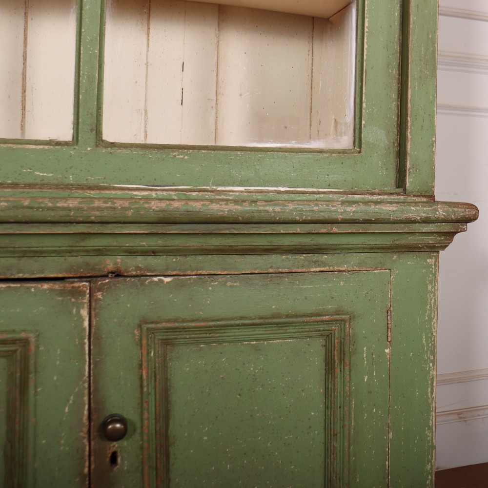 A large green painted timber cabinet featuring a two-door glazed upper section with multiple glass panes above a four-door solid panelled lower cupboard. View VII