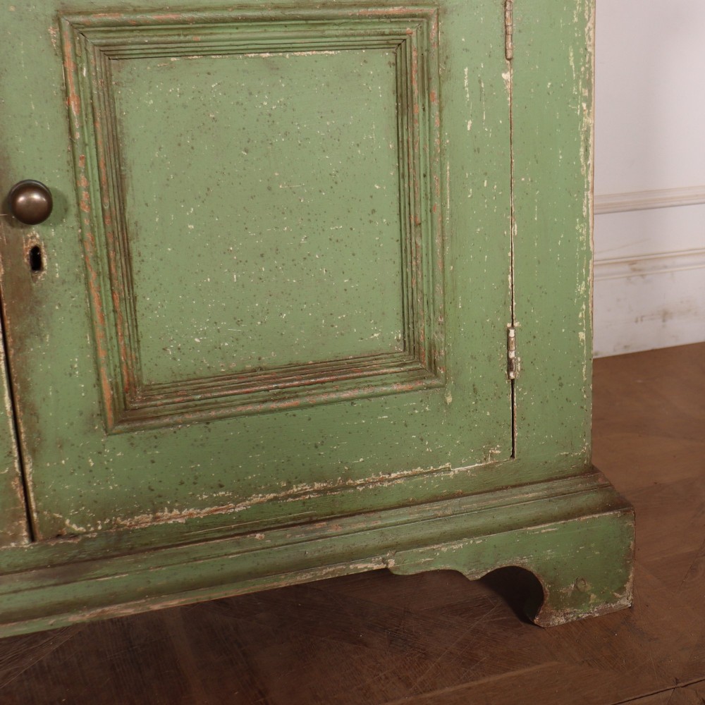 A large green painted timber cabinet featuring a two-door glazed upper section with multiple glass panes above a four-door solid panelled lower cupboard. View VIII