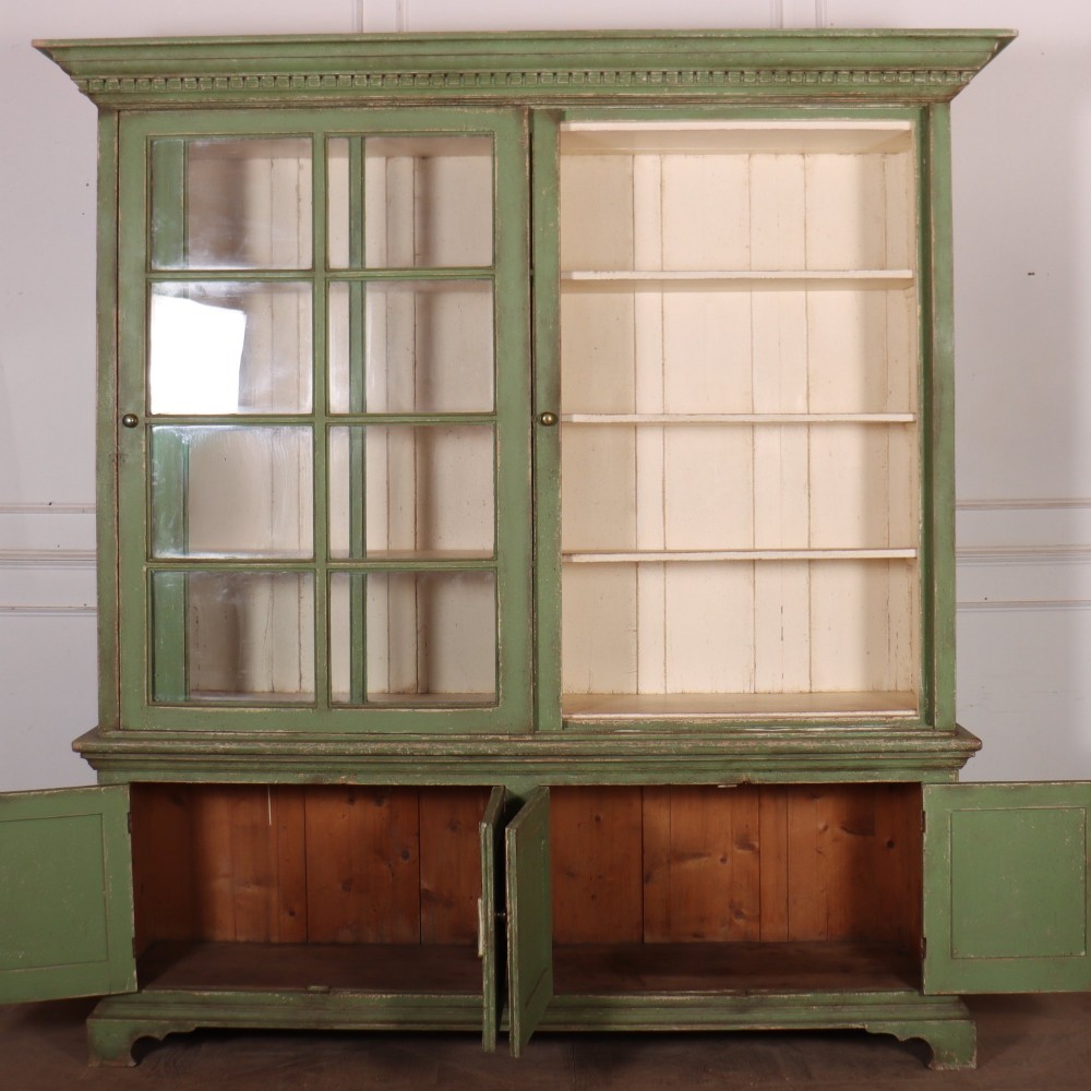 A large green painted timber cabinet featuring a two-door glazed upper section with multiple glass panes above a four-door solid panelled lower cupboard. View X