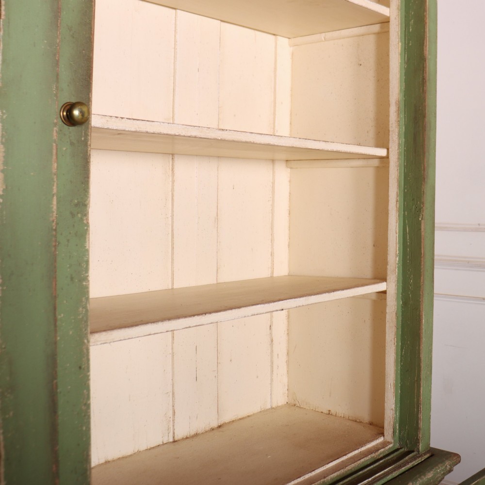 A large green painted timber cabinet featuring a two-door glazed upper section with multiple glass panes above a four-door solid panelled lower cupboard. View XI