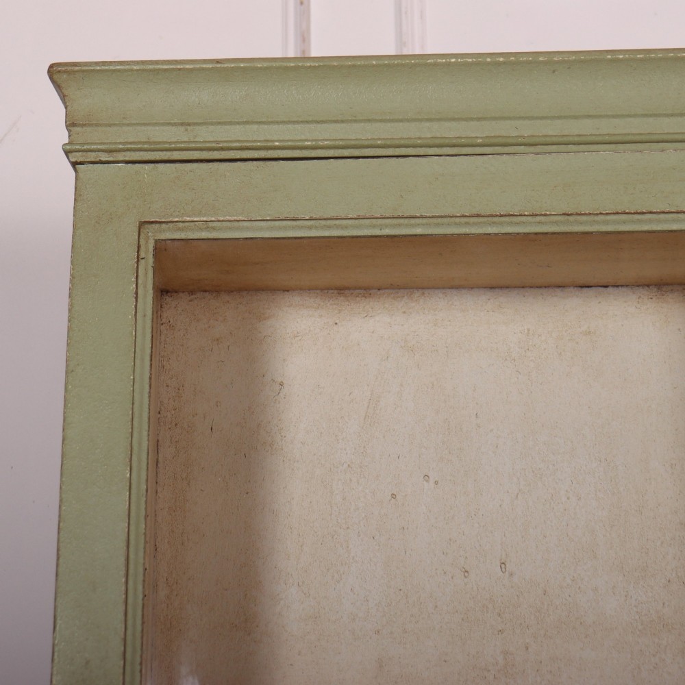 A tall sage green painted bookcase featuring two upper glazed doors revealing interior shelving, resting upon a base cabinet with two panelled doors. View II