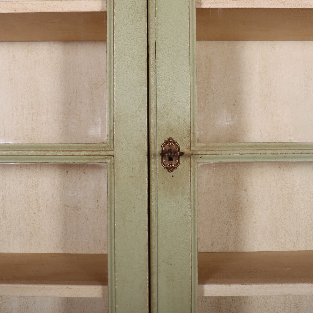 A tall sage green painted bookcase featuring two upper glazed doors revealing interior shelving, resting upon a base cabinet with two panelled doors. View IV