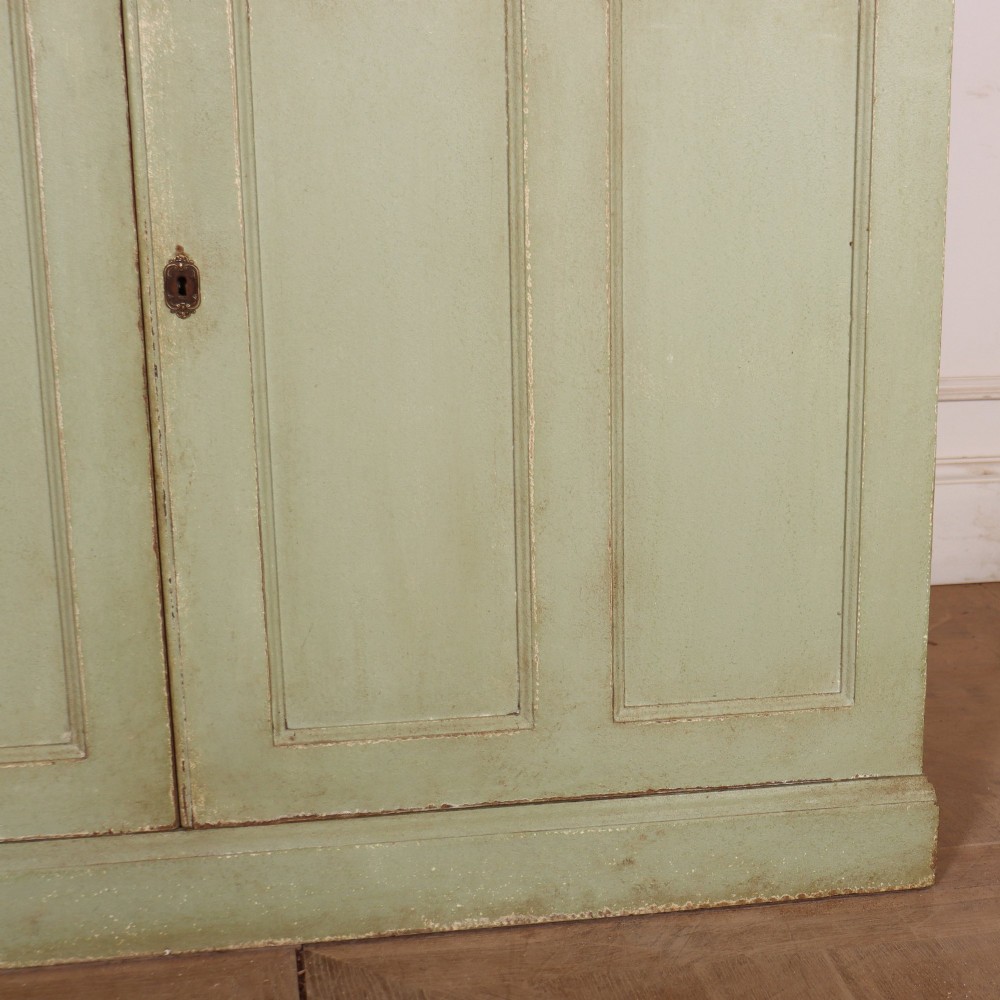 A tall sage green painted bookcase featuring two upper glazed doors revealing interior shelving, resting upon a base cabinet with two panelled doors. View VII