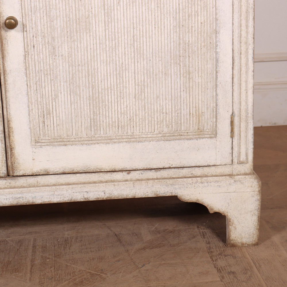 A pair of tall Swedish Gustavian style off-white painted bookcases featuring glazed upper doors with dark green interior backs above lower cupboards. View VIII