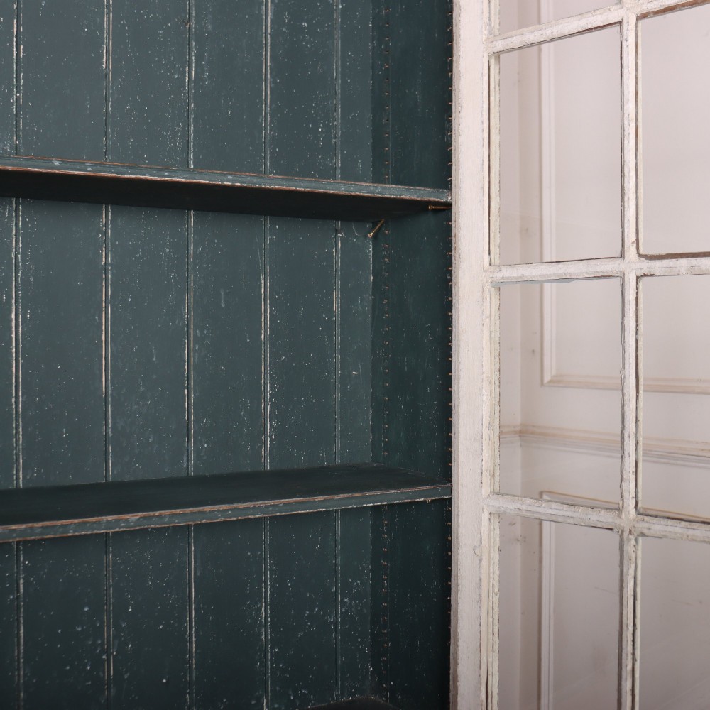 A pair of tall Swedish Gustavian style off-white painted bookcases featuring glazed upper doors with dark green interior backs above lower cupboards. View XII