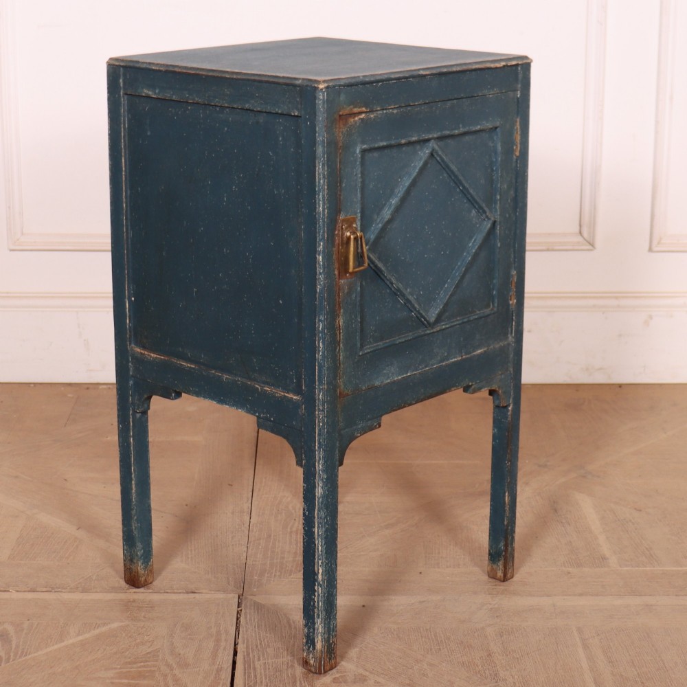 A small Swedish blue painted wood bedside cabinet with a carved diamond panel on the single door and a brass pull handle. View VI