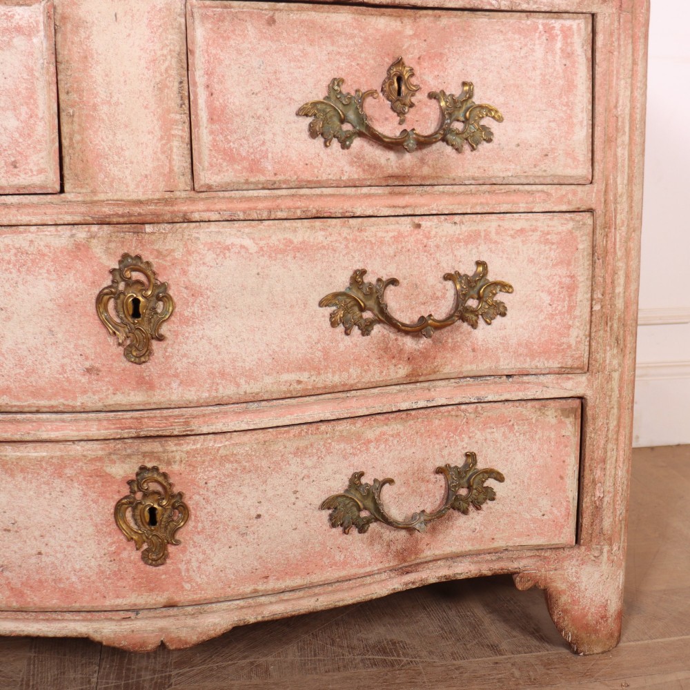 A Louis XV style French painted commode featuring a serpentine front, grey marble top, four drawers with rococo brass handles, and a distressed pale pink painted finish. View V