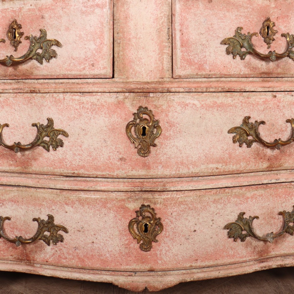 A Louis XV style French painted commode featuring a serpentine front, grey marble top, four drawers with rococo brass handles, and a distressed pale pink painted finish. View VI